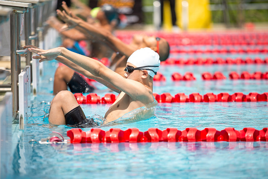 Swimmers in a pool swimming backstroke