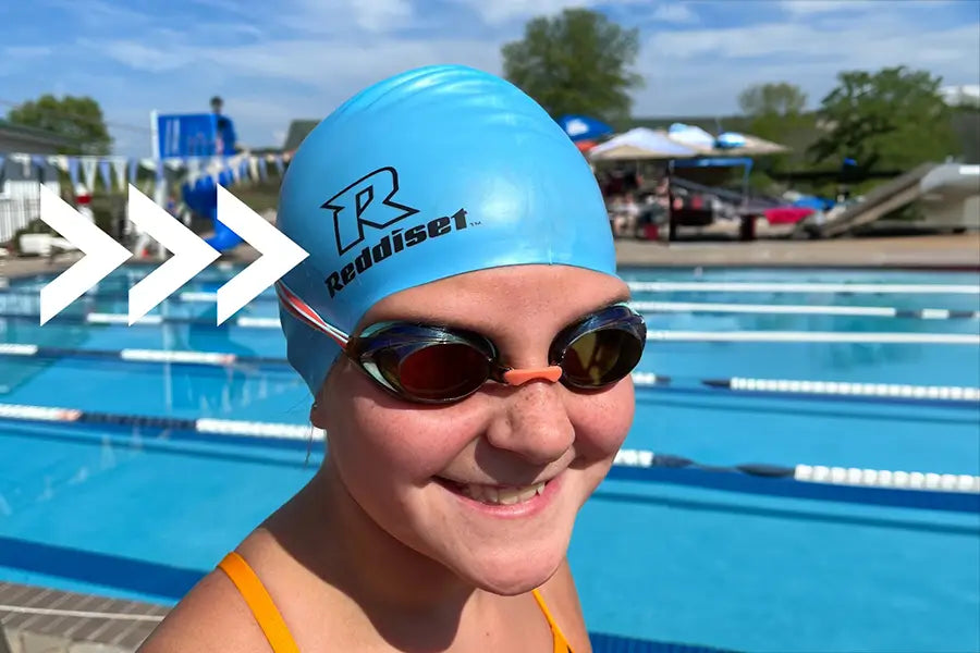 female swimmer next to a pool wearing a Reddiset swim cap