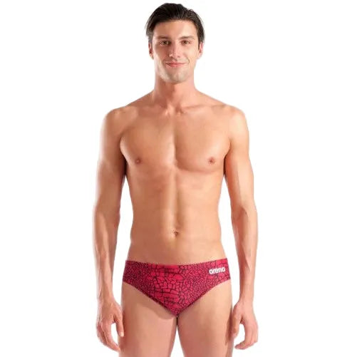 Man wearing a red patterned swim brief on a gray background